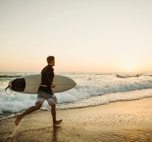 surfer carrying the surfboard on the beach